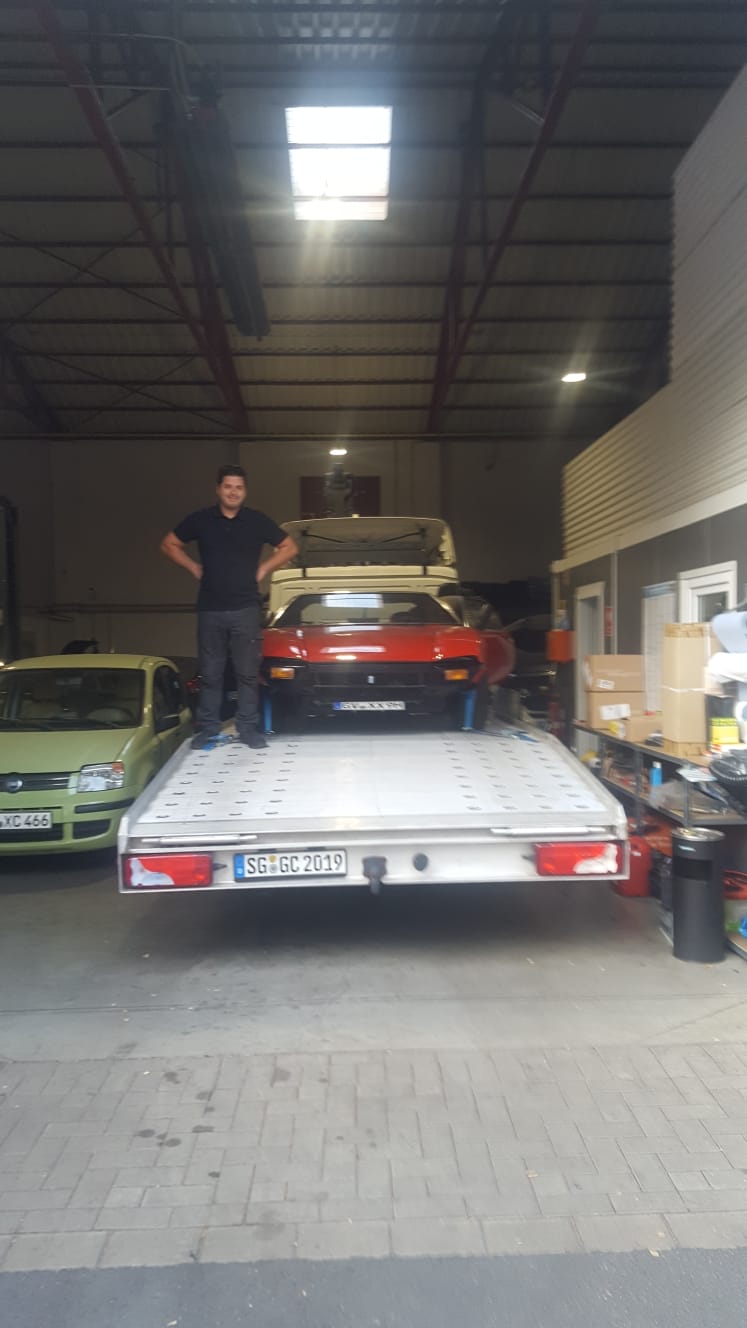 Mitarbeiter auf dem Fahrzeugtransporter in der Werkstatthalle